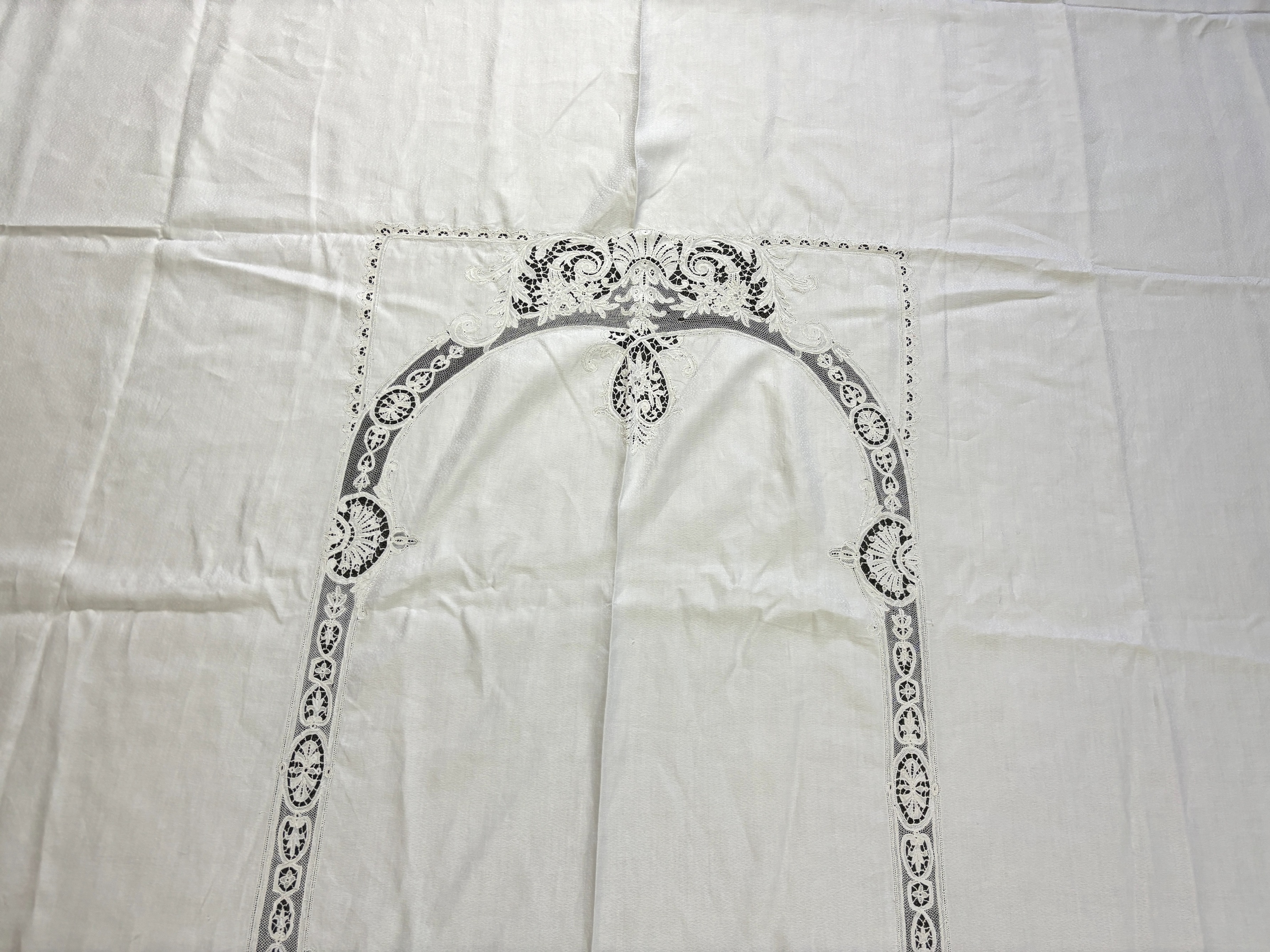 An Edwardian damask banqueting cloth 354cm long x 232 wide, worked with a central needle lace inserted cartouche, together with a smaller linen table cloth, 264cm long x 226cm wide, bordered with bobbin lace edges and si